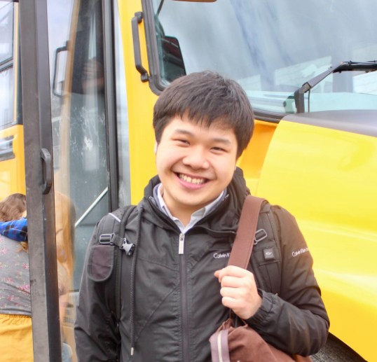 A photo of Sebastian in front of a yellow school bus.